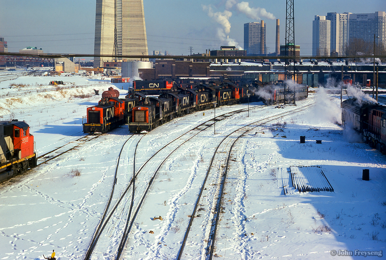 A large assortment of switchers fill the shop tracks at Spadina roundhouse, in the company of a few RDCs, a GP38-2W, and Tempo RS18m.  Note the turbo just poking out of Union Station.

Scan and editing by Jacob Patterson.