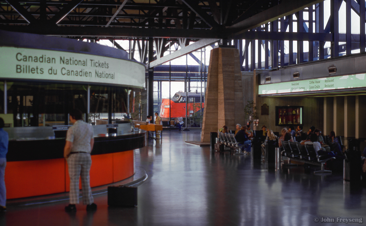 Passengers move through Ottawa's station, purchasing tickets, getting a meal at the restaurant, reading newspapers, magazines, waiting to begin their journeys.  CN 6518 idles in the distance.

Scan and editing by Jacob Patterson.