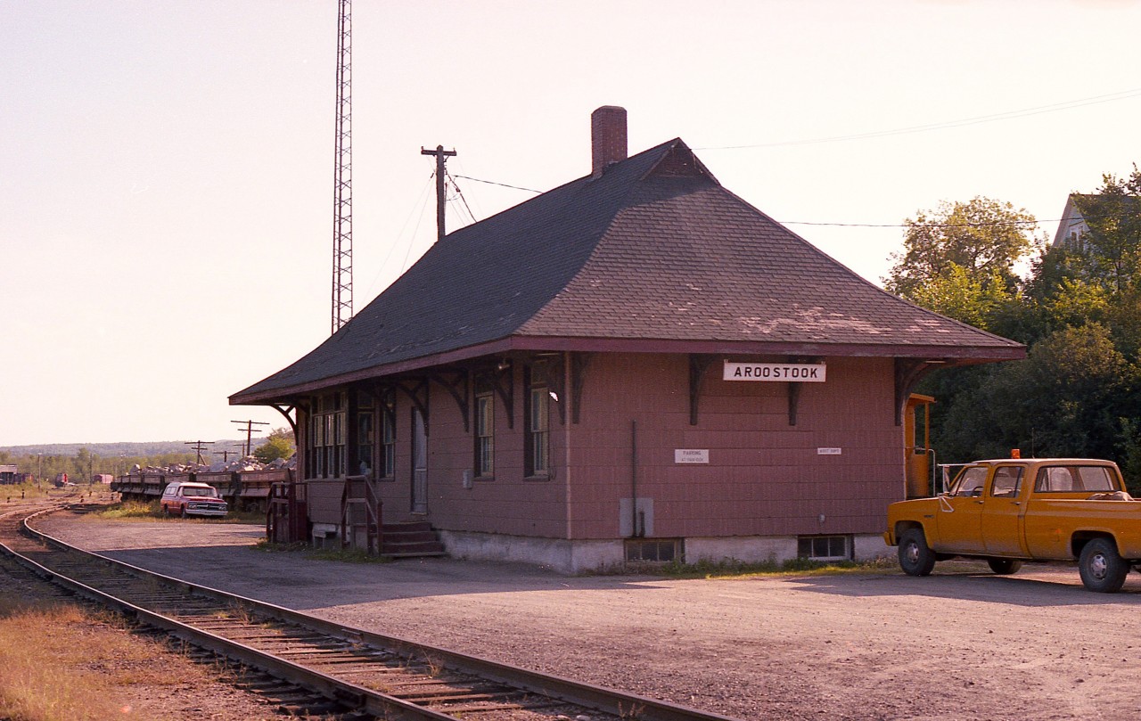 Aroostook was once a busy village. Situated near the Maine border, a station stood near the junction of the New Brunswick Railway (NBR) and the Aroostook Valley Rwy (AVR) connection. Now, the station, supposedly protected by Heritage; sits forlorn amongst the trees and shrubbery next to a trail; with only a fence to protect it from the elements.  The trail is the result of the track being lifted about 30 years ago. Hopefully this old frame structure, built in 1906, will see an honest effort to save it from slowly succumbing to the passage of time.