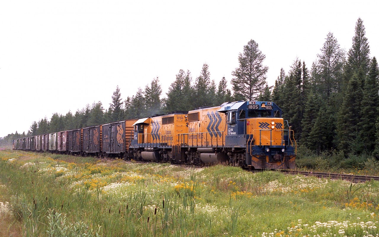 Rather overcast morning but at least there is lots of colour in the trackside growth as ONR 1805 and 1735 with a string of boxcars make their way to the pulp and paper company in Iroquois Falls.