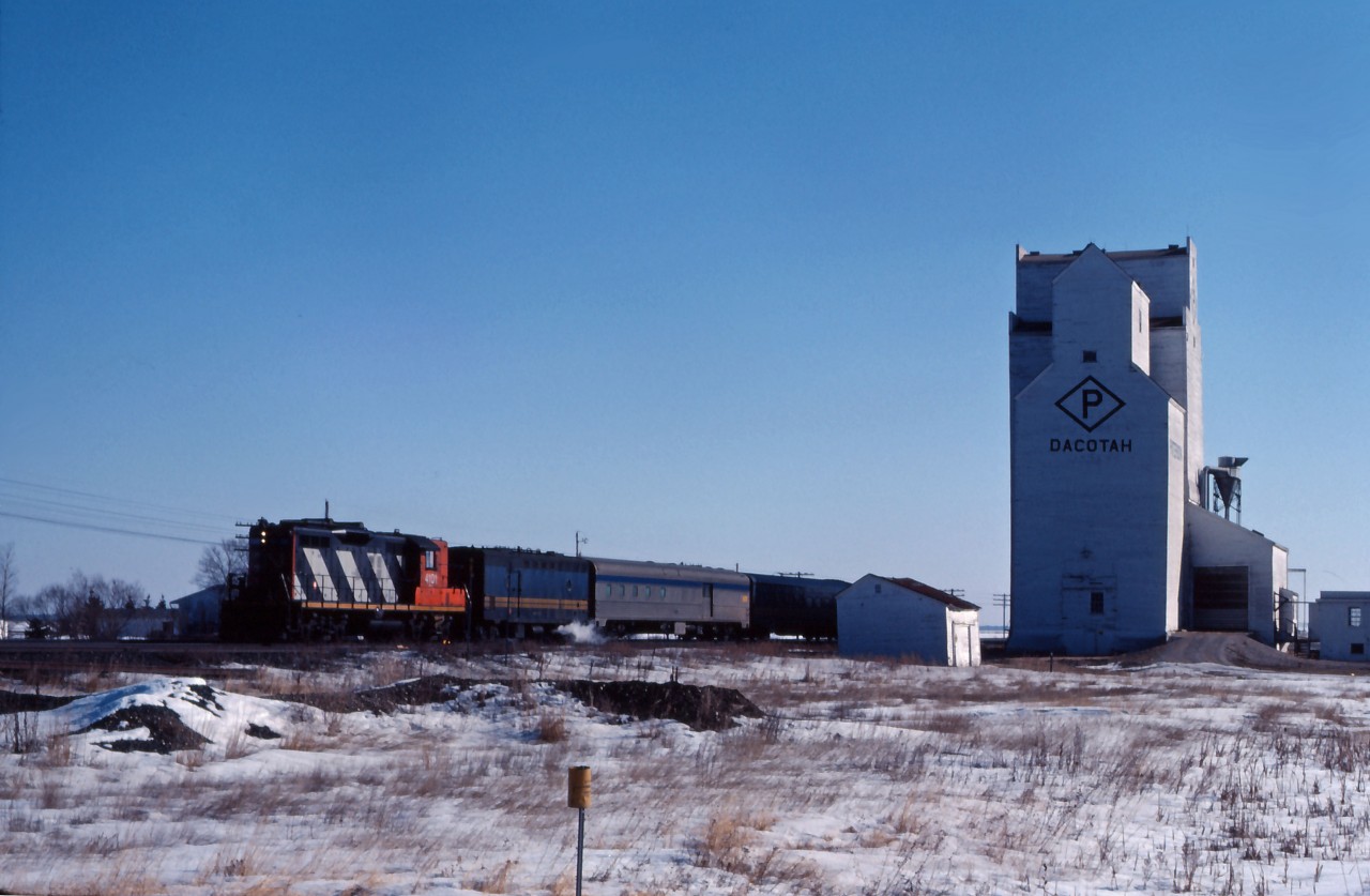 Although normally powered by an ex-CN FP9, occasionally No. 109 would be assigned a GP9 geared for passenger train speeds. Having moved to the prairies after years in passenger service out of Toronto, CN 4103 hustles the typically short train past the elevator at Dacotah (about 25 miles west of Winnipeg) on a cold but bright Saturday morning. In 1984, the 4103 will be chop-nosed and re-manufactured to GP9rm 4104.