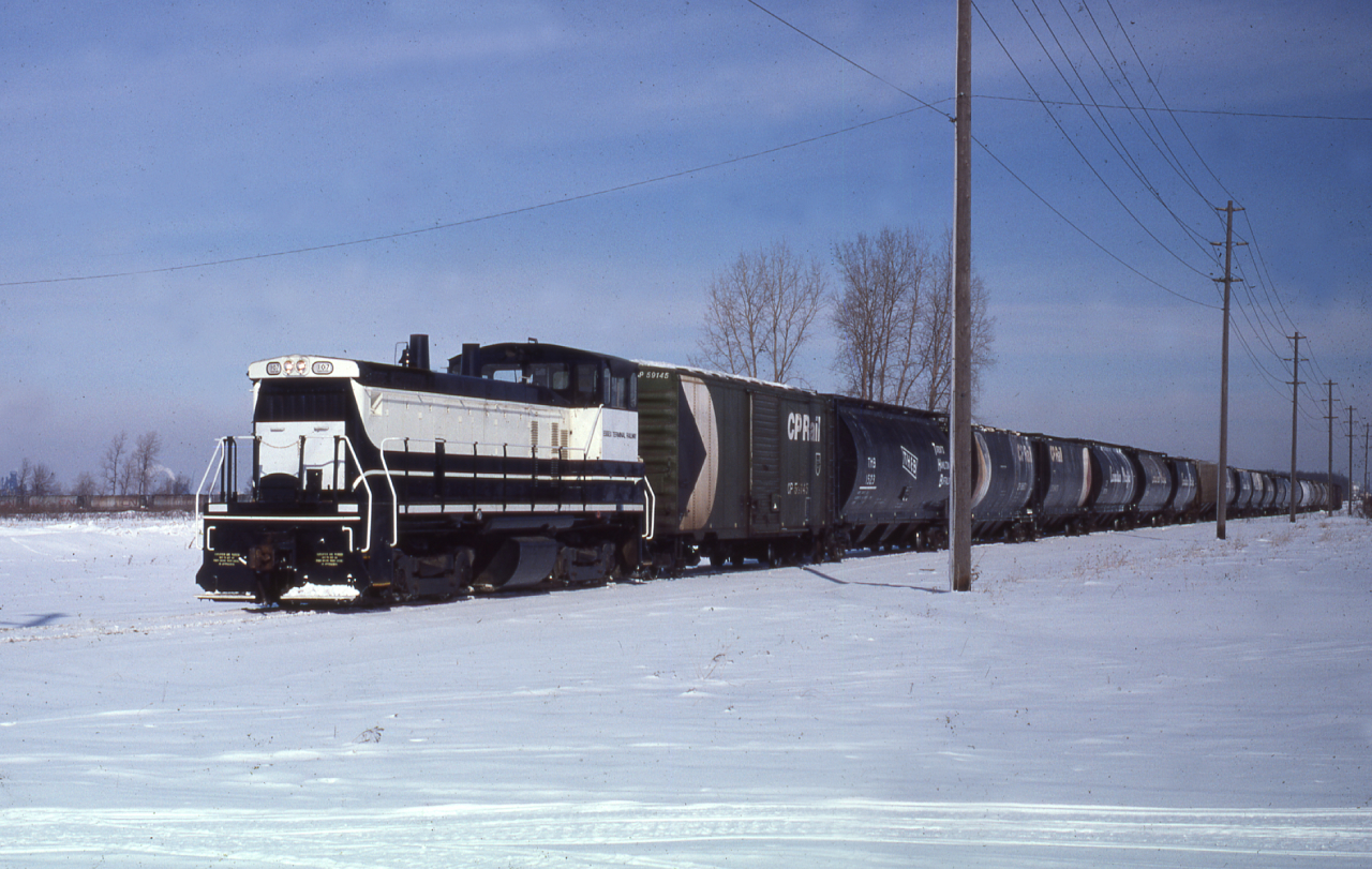 Pictured is ETR 107 with an impressive cut of cars, date is a rough estimate, ETR 107 acq. 7/1977 (ex DD-GM 113, nee EMD 113) SW1500 EMD 37436 4/1971.

Note the CNR Cylindrical hoppers in the back on the left. 

From Old Time Trains: This unit had been a plant switcher first at EMD in La Grange and later at GMD in London.
It had problems with the sharp curves in the GMD plant and was swapped for ETR 102 an SW8