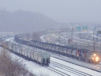 BCOL 4646 leads CN X321 as it approaches Turcot Ouest in the snow. Up front is a string of black TankTrain cars. At left are grain empties from the Port of Montreal that CN 500 had left there earlier in the day.