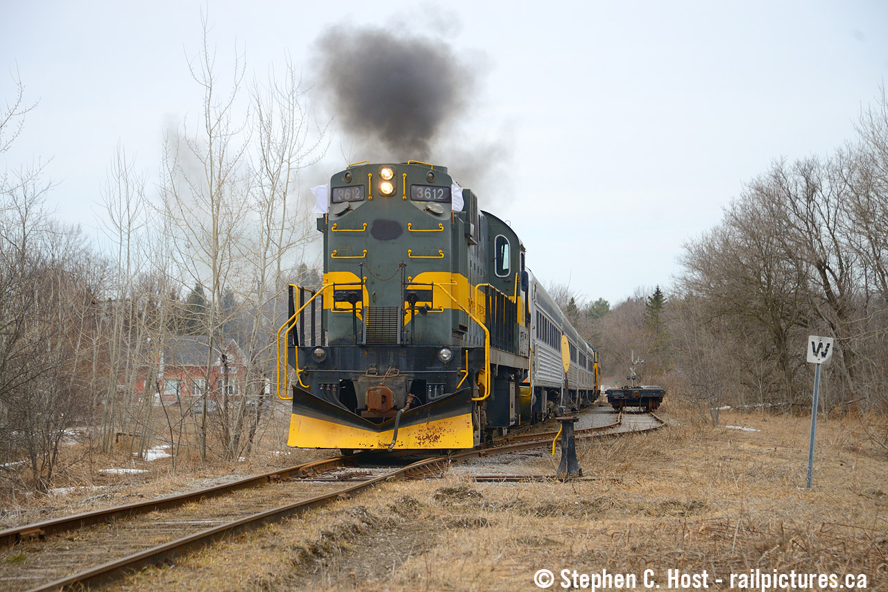It took three months, and it was only supposed to be a single day of movements back on December 21 2025, but the Railroad Equipment Restoration Association pulled it off. Despite numerous attempts over the winter, extreme cold, snow, and motive power that can be best described as "temperamental", warmer weather coupled with mechanical repairs to 3612 and the movements started actually going off without a hitch. Goodwood, a hamlet that once had a Station and passenger trains, along with a grain elevator and frequent service, was mostly silent for the last few decades. Between December and March, Goodwood became a beehive of activity: Mechanical repairs were conducted on equipment, locomotives were watered, repaired and tested, crews reported for duty and when everything worked, trains operated along the Uxbridge sub between "the dip" (A location 4 miles south of Uxbridge) and Lincolnville all based out of Goodwood. The best part? It was all done with locomotives with prime movers designed in 1944 and 1951, MLW/ALCo's, which as noted in December, are a dying breed in Ontario.
All of it came to an end on March 29 2026: Pictured the last cut of cars is now ready to go, mechanical modifications to the cars are completed, and the last order of business is to load the train with *everything left* that wasn't already towd down in the coaches. You see, the RERA purchased *everything* that the former YDHR owned, including all sundries: this included old souvenirs, TV's, mechanical equipment, uniforms, stuff in storage, historical artefacts, everything. The RERA was tasked, contractually, with removal of it all and it took a team of about 10-15 people to hand bomb what remained all into these coaches and send it to Saskachewan and North Bay. After the picture you see above the train would stop on the crossing and the last of it would be loaded from waiting trucks and vehicles. Then they'd reverse back to Goodwood to make one final run out of town, blasting the horn, again, to a gaggle of waiting cameras and a few locals observing the end of their tenure on the Uxbridge subdivision.
What does the future have in store for this line? At the moment, nobody knows for sure, but it would appear GO transit isn't exactly done with the railway and neither is the town. The town is working on a "railway district improvement plan" and their plans show trains calling at the Uxbridge station but with much improved lands surrounding what  I would call a GO station platform. The town and Metrolinx are also re-negotiating the lease in 2026. Could GO service happen? Is a 6 car train that far off the mark when it's only a 10 mile run and about 30 minutes from Uxbridge to Linconville at 30 MPH, then they can blast off at the Uxbridge's 50 MPH after stopping at Old Elm. Until the tracks are ripped out, never say never. A train or two to Uxbridge would also help the town re-develop the lands and reach the Province's goals of urban intensification, by right, near transit stations. We'll just have to see what happens from here. In the meantime, the 244's and 251's are silent in Uxbridge and the York Durham's legacy is now gone for good and on to better things.
Over the next few days and weeks, all this equipment would move over Metrolinx and CN to Mac Yard, and then to North Bay and Kronau, Sackachewan. For updates on the equipment and their plans, visit the RERA Canada website at www.reracanada.ca where announcements are yet to be made as I type this. I couldn't be happier to see the equipment at least preserved, it took a ton of money and effort to pull this off and folks, please give the RERA a good look. They deserve it.