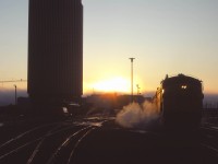On what promises to be a nice September day, the sun rises on the westbound Super Continental being serviced in Edmonton. Alas, in a little over two months, “the Super” will no longer call here—replaced by day trains Winnipeg-Regina-Saskatoon, Saskatoon-Edmonton, and the “Rupert Rocket” extended to Edmonton. The passenger station was opened by Canadian National on 14 February 1966, and the CN Tower office building officially opened on 4 November 1966—at the time, the tallest office building in Western Canada.  Eighteen years after this photo was taken (on 3 September 1989), the restored Super Continental began the westbound pull-in/back-out move as CN phased out operations in downtown Edmonton. VIA would finally move to its current station near the Yellowhead Trail and Walker Yard on May 29, 1998. CN moved its office personnel out of the Tower a decade later.