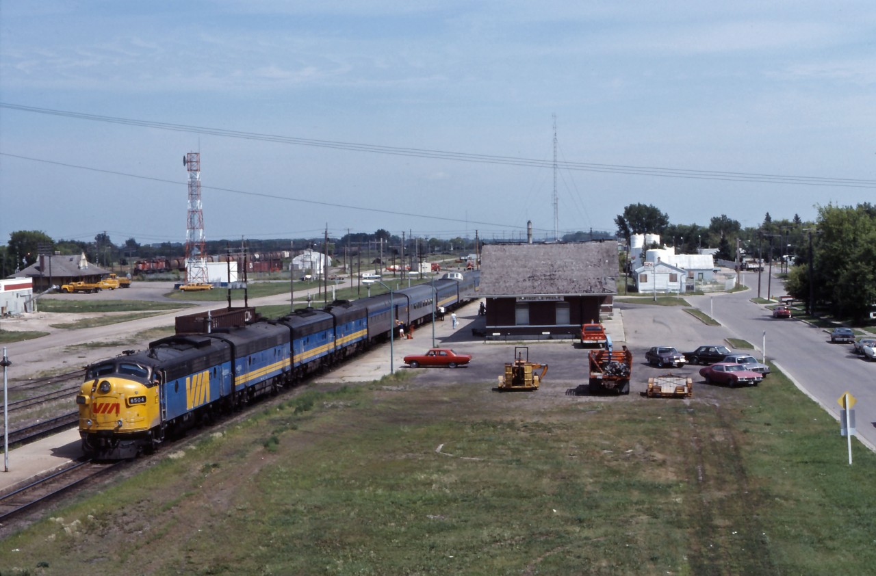 The"Canadian" makes its station stop at Portage la Prairie on a beautiful summer afternoon in 1984. Although the "Panorama" now runs Winnipeg-Edmonton (and three days per week to Prince Rupert), No. 1 is still handling the bulk of the transcontinental traffic--normally an 18-20 car train in the summer. Powered by an ABBB set of former CN F-units, just up ahead the Queen of the fleet will take the connecting track between CN and CP to resume its traditional route to the coast. (Also note the freight in the background near CP's Portage la Prairie station, waiting to following the passenger west.)