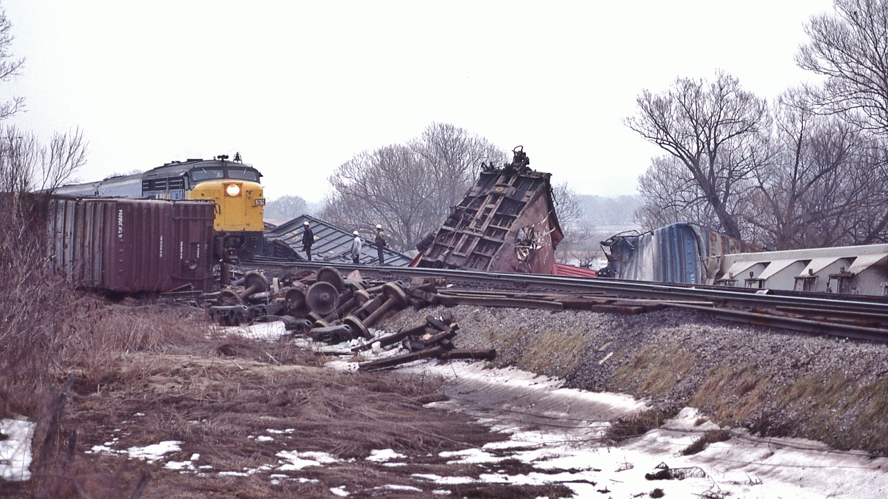 More action at CN Beachville, February 18, 1984 Kodachrome by S.Danko


VIA 6762 west creeps onto wreck site at a stately 10 m.p.h. Note the downed communication / hydro cables.


February 14, 1984: A 25 car CN train derailed four miles west of Woodstock ( Beachville) causing $1 million damage. Half mile track torn up, propane tankers included in consist. Heavy rains blamed for weakening the track bed. Reportedly every spring new remnants of the derailment can be seen along the Beachville Thames River Trail – pushed up by the winter frost.


More


  VIA 6765 east   


sdfourty