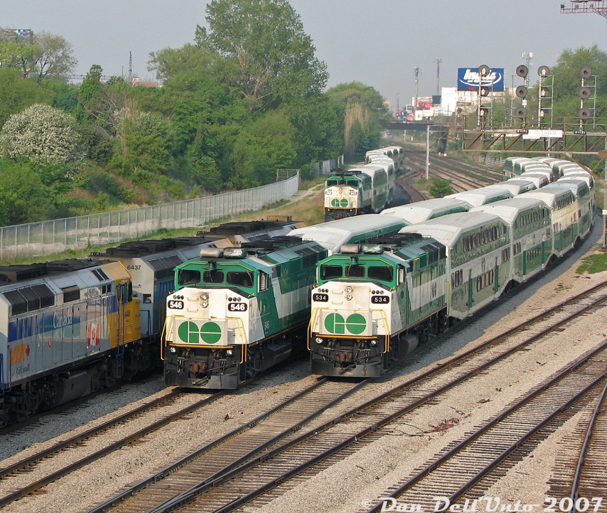 Another warm spring morning down at Bathurst Street, back when you could still taste the morning smog and haze in the downtown Toronto air. Three GO Transit F59PH units swarm Bathurst Street, right where the Oakville Sub ends and the TTR Union Station Rail Corridor begins: 546 is inbound with Lakeshore West train #454, passing 534 trailing equipment move #E472 (off the Lakeshore line) waiting for the light to head westbound to Willowbrook Yard. Unit 543 also lingers in the background on the High Line bypass, on equipment move #E152 (off the Milton line) also bound for Willowbrook and waiting on a light. One had to be on top of things and know what was coming in off what line to get all the train numbers - I had made an Excel "cheat sheet" with every single train inbound or outbound to Union Station, manually scraped from every GO Transit, VIA and ONR schedule, and was usually able to put train numbers to most consists and equipment moves.

A trio of VIA F40PH-3D units pause on #1 "The Canadian", backing a supersize 30 car train inbound to Union Station (with a 4th F40 on the rear, piloting eastward). It's 8:14am now, and the flood of F59's and bilevels at Bathurst Street would die down by 9am, when the pinnacle event of VIA #1 departing Union Station topped off the morning. One would then depart for the day's other work or educational activities, satiated by an hour or two of the morning action.