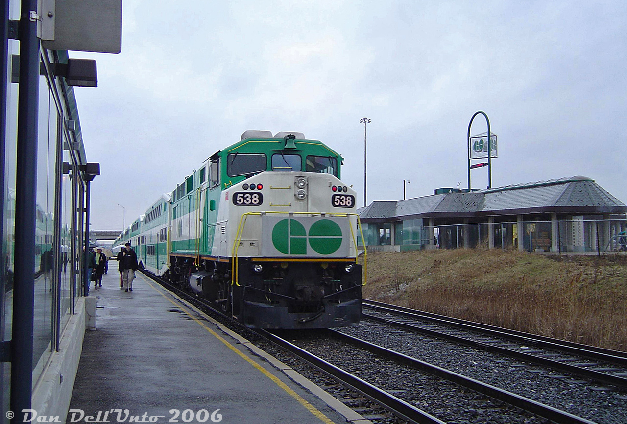 Another one from the "stations that aren't there anymore" files: Shooting an F59PH passing by the Bramalea GO station was trickier than one thought, as the CN RTC typically lined GO trains onto the south track for the easy transition to/from the Weston Sub at Halwest, thus north track shots like this (without the elevator building in the way) weren't easy to come by. Here, Georgetown line train #207 (the 4:45pm from Toronto making all stops, our ride home) powered by GO Transit F59PH 538 departs in the rain, past the station building as umbrella-toting commuters head for the stairwells and elevators.

The old Bramalea station, a unique and interesting low-profile mid-70's building original to the opening of the line in 1974, would be demolished in 2021 and replaced with a new Metrolinx-style GO station, bus terminal, and very large parking garage. There was some interesting wooden truss work under that roof, which always seemed to be missing a few of those light green shingles (chic for the era, no doubt). A bit of a shame there was never a station-side platform for easier access.