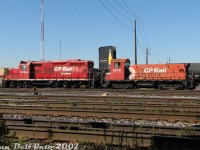 Typical lowly yard power on CP back in the 2000's was often a rebuilt GP9u-slug set. In the 90's CP had a bunch of surplus low horsepower GMD switchers, both aging and underpowered. Converting some into yard slugs was an economical way to reuse old power and give the GP9u's some extra "oompf" around the yard (where low-speed lugging ability was more important than speed or horsepower). Having one less engine between the pair also saved on fuel, and later when some were equipped for beltpack operation (note the antenna planes on 1598's cab and beacons), it saved on manpower as well.<br><br>Sitting next to the yard office near the Runnymede Road underpass, CP GP9u 1598 and former SW8u slug 1012 lounge about the afternoon at the split West Toronto/Lambton Yard awaiting their next assignment. There was usually a set here for flat-switching the yard, with local power (typically multiple pairs of GP9u and/or GP38-2 units) parked on <a href=http://www.railpictures.ca/?attachment_id=12954><b>another track</b></a> near Runnymede Park.<br><br>The slug conversion was pretty basic: the units would be modified so their traction motors would receive power from the GP9 "mother" unit. The engine block was either left in, or removed and the space filled with a concrete block. Cab windows and radiator openings would be plated over or left intact, and painting usually amounted to just a patch job and renumbering. This late in the game, CP wasn't putting any money in the slugs aside from keeping them running, so most wore their old action red colours until retirement (the next year, 1598 got an overhaul and brand new coat of paint, but not a drop was forthcoming for 1012). When this set was retired in 2013, 1598 was traded in on the GP20C-ECO program and scrapped, and 1012 was sold for scrap to SLM Recycling in Welland.