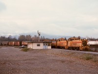 Due to its regular route from New Westminster to Huntingdon unavailable due to bridge work, the BC Hydro eastward Valley Freight detoured over Canadian Pacific lines (Westminster, Cascade, and Mission subdivisions) on Monday 1975-11-17, and due to six-axle units forbidden on CP at Sapperton near New Westminster, four SW900s, BCH 907 + 902 + 906 + 910, powered that train, and it is shown here at CP’s Coquitlam depot and train order office JN (from Junction, versus YD in the yard office control tower in the yard) at 1500 PST.

<p>Years later, that depot in Port Coquitlam was renamed Port Coquitlam to minimize confusion for Westcoast Express commuter train passengers, and that area is now an extensive commuter rail and transit bus depot.