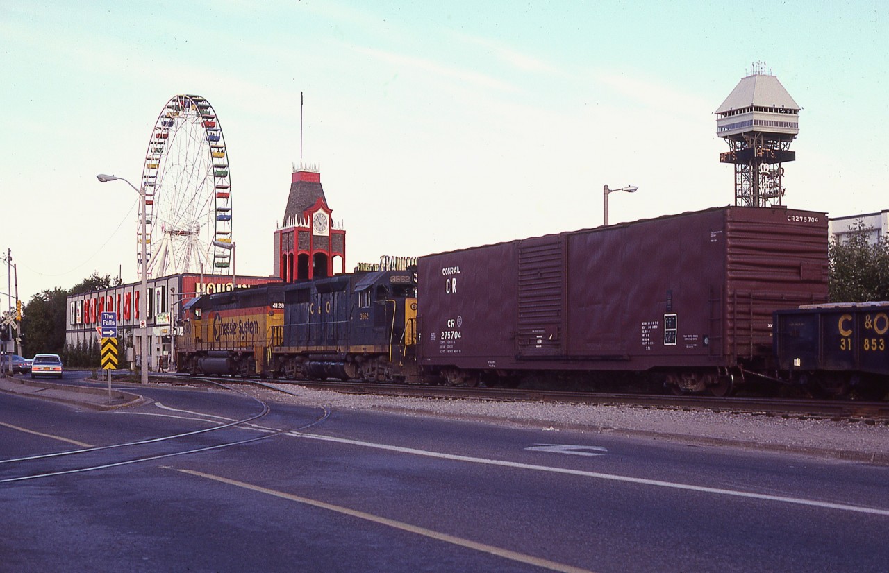 It appears strangely quiet on touristy Clifton Hill this particular evening.  No idea why. Maybe they heard the power coming? :o)  B&O 4128, C&O 3562 are heading eastbound to the USA with a long train. The track in the foreground was the spur to the Nabisco Shredded Wheat facility.  And it looks like it has not been used in some time.
Certainly has been a LOT of changes since I shot this; notably the tracks removed 20 years later.........
