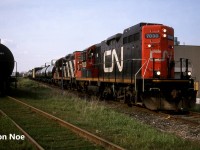 The CN 15:30 Kitchener Job is viewed switching in Elmira, Ontario on the Waterloo Spur with a lengthy train and GP9RM’s 7030 and 4141. At the time, the job only operated with two units when it was necessary and on this day, both Nutrite and Sulco Chemicals in Elmira were receiving several cars. The springtime was always a busy period for Nutrite receiving hoppers. Also, the crew had a loaded lumber car that they would set-off at Fairway Lumber in St. Jacobs on their return trip south to Kitchener. 