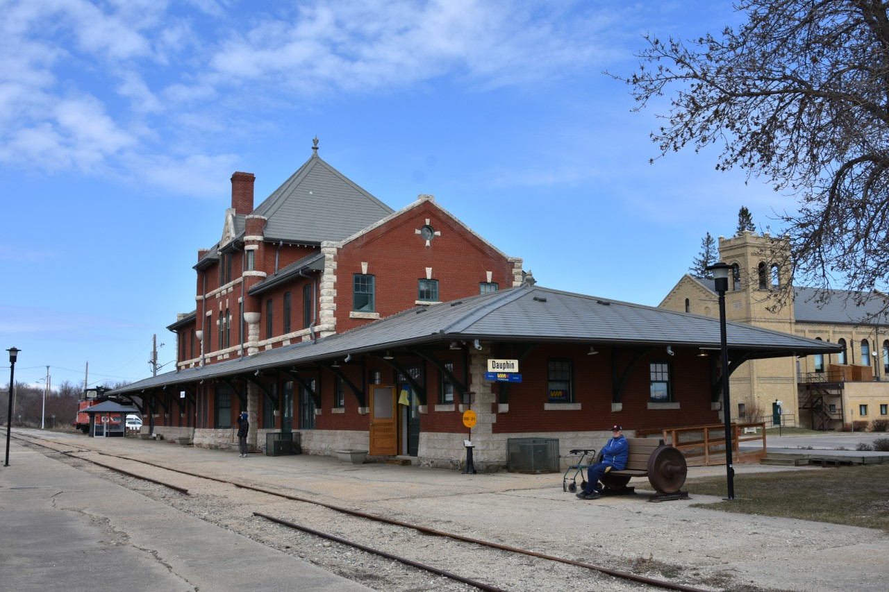 Doesn't look a day over 114  
The majestic CN station in Dauphin, MB was built in 1912 by the Canadian Northern Railway and is still looking magnificent 114 years later on May 1, 2026. 
It was constructed to a design by architect John Schofield and was designated a Heritage Railway Station of Canada in 1990. 
Being a scheduled stop for both VIA 693/692 the north and southbound Winnipeg to Churchill trains, passengers have an opportunity to detrain for a leg stretch, some fresh air, and a chance to snap some pics of the station, other local architecture, or have a quick visit to the Dauphin Rail Museum inside the station. :-)