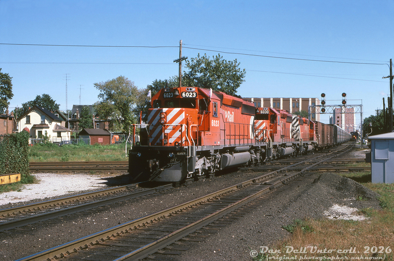 It's SD40-O'Clock at West Toronto as three of CP Rail's many GMD SD40-2 units pound the diamonds heading westbound on the North Toronto Sub, crossing the double track mainline of CN's Weston Sub and the CP MacTier-Galt connecting track. CP 6032 (flying white extra flags) leads 6030 and another unknown 6000 on the north track, while further back on the south track past Osler there appears to be a local freight approaching, lead by an SW1200RS.

The old West Toronto diamonds here, dating back to the steam era, would see many more SD40-2's cross before they were removed after the Metrolinx/GO Transit West Toronto grade separation project was complete in May 2014.

Original photographer unknown, Dan Dell'Unto collection slide.