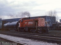 The engineer of CP Rail S3 6545 notches the little unit's throttle up, working around CP's <a href=http://www.railpictures.ca/?attachment_id=35550><b>Parkdale Yard</b></a> in the Liberty Village part of Toronto. In the background behind the yard tracks is the John Inglis appliance factory, and other industrial buildings that once populated this area. 6545 was just one of many little steam era Alco/MLW S2/S3/S4 diesel switchers CP employed to handle industrial and switching duties in and around the Toronto area. In consist is extended-height CP newsprint boxcar 84981, increased in size to hold newsprint rolls stacked double high.<br><br>This area is now heavily gentrified, the last of the Inglis plant (and its <a href=http://www.railpictures.ca/?attachment_id=11444><b>iconic billboard sign</b></a>) have been demolished, and the rail corridor through here is now a giant <a href=http://www.railpictures.ca/?attachment_id=25804><b>trench</b></a> ducking under Strachan Avenue. The last of CP's Toronto-assigned Alco/MLW switchers were retired in the mid-1980's with the closing of CP's <a href=http://www.railpictures.ca/?attachment_id=45795><b>John St. Roundhouse</b></a> downtown.<br><br><i>Bill McArthur photo, Dan Dell'Unto collection slide.</i>