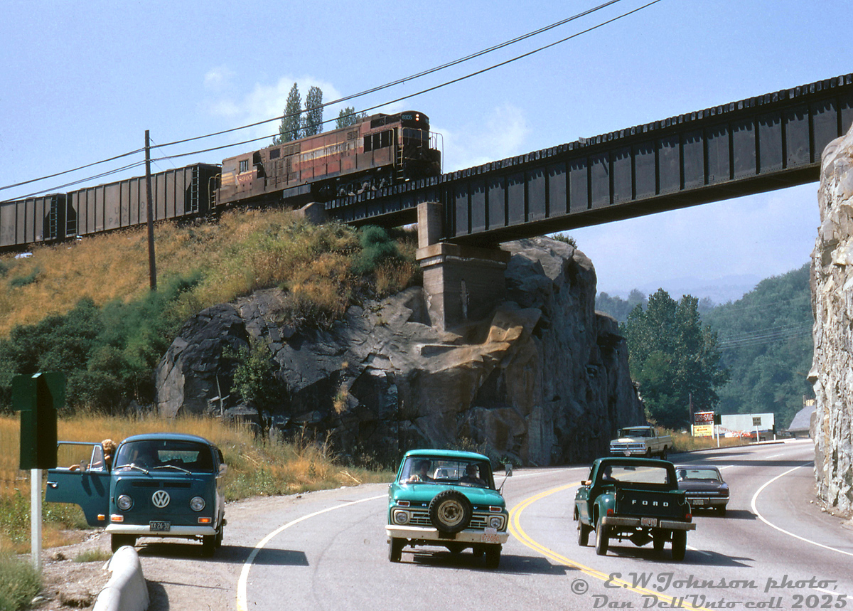 High over traffic on the Paterson-Trail Highway below, Canadian Pacific H24-66 "Train Master" 8905 passes above on the Rossland Sub at Warfield, BC, climbing the grade to the nearby smelter at Trail, BC. The photographer's green VW bus sits pulled over to the side, with a companion along for the ride watching the Train Master come into view and cross over the bridge.

Once part of a group of 21 units, by the early 70's the trio of CP 8900, 8904 and 8905 were based out of CP's Nelson BC shop for maintenance, and assigned to Trail for switching the Cominco smelter. This assignment also involved bringing trains up the Rossland Sub's steep Warfield Hill, a heavy drag-type assignment that once involved CP's only Lima Shay steam locomotives (units 1901-1903) that brought cars up the steep grades (4.1%!) and switchbacks. "Shorty vans" were used because of a switchback enroute, in order to allow the maximum amount of cars (two vans, 437110 and 437111, were shortened in 1944, and continued to see use into the 1970's).

Over time the trio of Trail units became the last three Train Masters on the system (as Montreal's units were retired in 1972). They were then sent to Alyth Yard for hump service in September 1973, and stored in December 1975 (replaced by GP7's due to complaints about their exhaust fumes getting sucked into the yard office by the hump). After being "Tied Up Unserviceable" in 1976, the order was given from the higher ups to scrap them. 8900 and 8904 were cut up at Ogden Shops in August 1976, while 8905 was set aside as part of CP's historic diesel collection earmarked for future preservation (8905 now resides at Exporail/CRM in Delson, QC, the last Train Master in existence).

A story from the late Bruce Chapman was before they were reassigned to Alyth, the motive power department tried to find them another home for them to work out of. They were told in no uncertain terms by the brass out east that there was absolutely no place for them to be used on the Eastern Region (that had retired the last of theirs from transfer service: Montreal-based units 8901, 8909 and 8917).

Eric W. Johnson photo, Dan Dell'Unto collection slide.