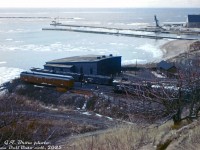 This hillside view shows Canadian Pacific's roundhouse and turntable at their yard in Goderich, Ontario. An abundance of "slab-side" covered hoppers and an old passenger car converted into an OCS work car are present. At this time, some of the harbour and salt facility in the background had not yet been expanded out.
<br><br>
The turntable survived into the 1980's but the roundhouse appears to have been demolished just after the end of the steam era (gone in this <a href=http://www.railpictures.ca/?attachment_id=29867><b>Bill Thomson photo</b></a>). CP abandoned their Owen Sound Sub between Orangeville and Owen Sound in December 1995.
<br><br>
<i>G.T. Brow photo, Dan Dell'Unto collection. This old slide had badly colour shifted and washed out, it took some coaxing to get it cleaned up and presentable.</i>