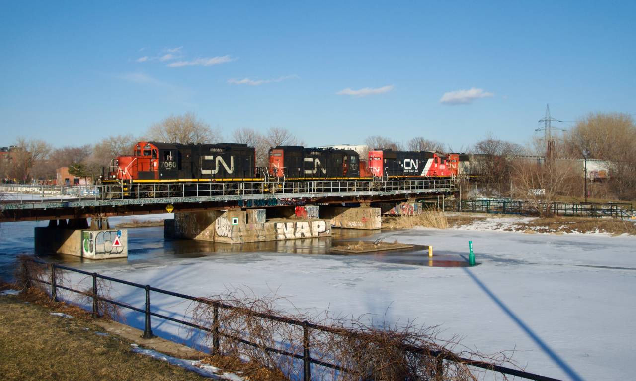 CN 543 is returning from  the Port of Montreal with CN 7060, CN 7017, CN 4712 & IC 9639 for power as it crosses the Lachine canal. The GP9s had picked up CN 500's dead power off of the nearby East Side Canal Bank Spur a bit earlier that afternoon.