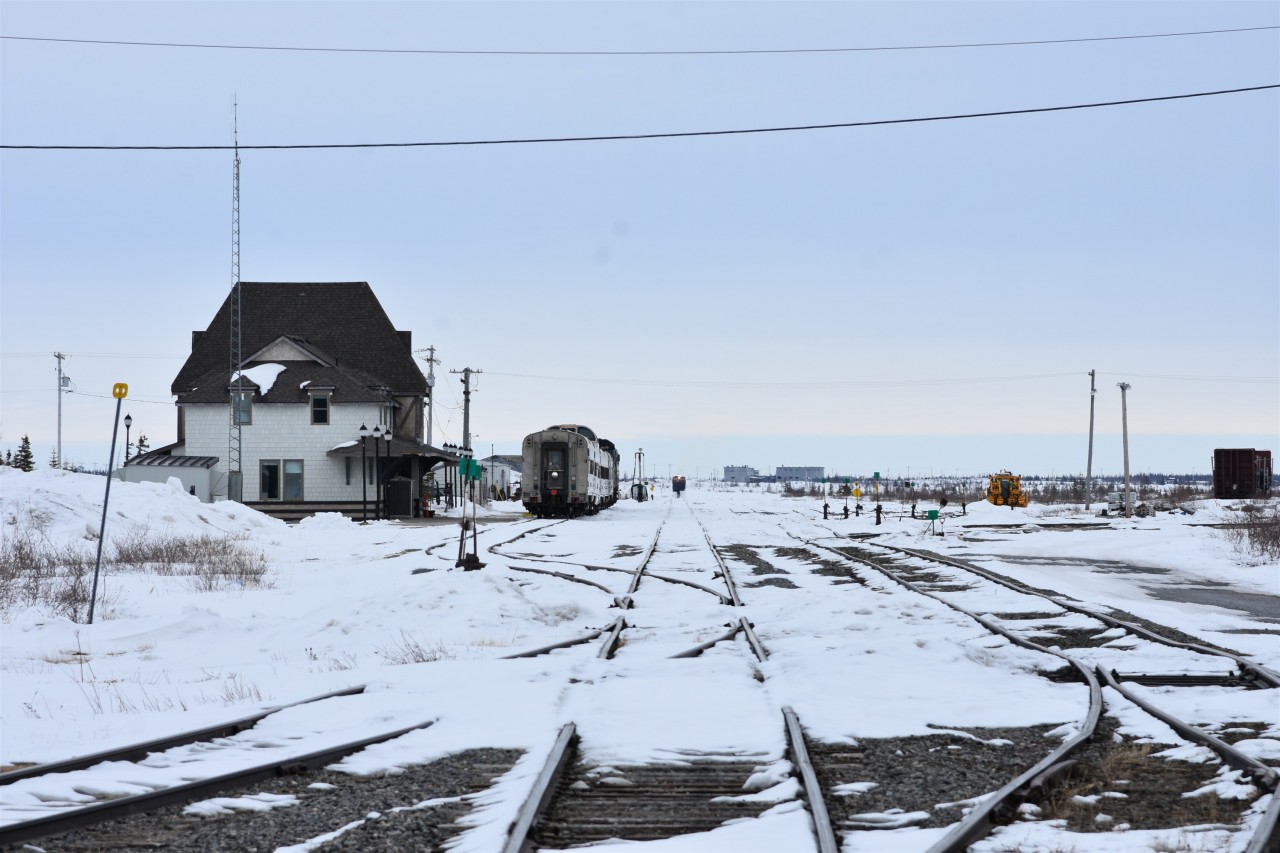 What light through yonder horizon breaks?  
I know that very familiar white light on the tail end of VIA 693, but that odd combination of lights on the approaching main line train in the distance has grabbed my attention. 
After snapping several shots, and with the movement a little closer, it became quite evident that the HBR way freight was arriving in Churchill with a single-track snowplow on the point. 
It's kind of ironic that the way freight with the plow up front followed the VIA passenger train from Thompson to Churchill. Go figure! 
Capturing the plow was a great bonus to my day in Churchill. :-)