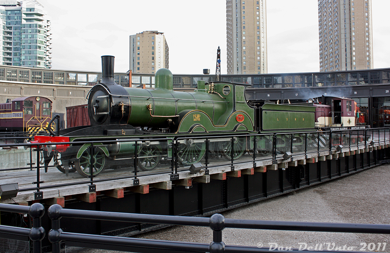 Fitting in perfectly with her surroundings (s steam-era roundhouse, and restored turntable) London & South Western Railway 563 'Vicky' (a T3-class 4-4-0 passenger steam engine originally built in 1892, and retired in 1945) is spun around on the ex-CPR John Street Roundhouse turntable, in preparation for being put away inside the roundhouse. TRHA's CLC-Whitcomb center-cab switcher 1 is seen doing the honours.

At the time, L&SWR 563 had been loaned for 'The Railway Children' production being put on in a tent set up on the Toronto Railway Museum's grounds, and was moved around by the TRHA's switcher during and after the production. Its current home is at the Swanage Railway in the UK.