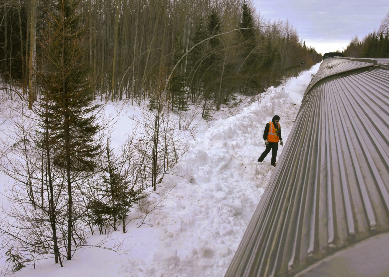 No HBD, no problem!  
There are a few new electronic Hot Box Detectors on the HBR's subdivisions between The Pas and Churchill, but where they have yet to be installed, the hand-held laser gun method is deployed every 40 or so miles along the remote route. 
Seen here is VIA 692's second engineer, who has climbed down from the left side of the locomotive cab at Munk, MB Mile 269.0 on HBR's Thicket Sub. to use a laser temperature sensing device to check the axle bearings on each car in the trains consist. 
A slow roll-by of the entire length of the train from locomotive to the tail end sleeper, a stop, a crossover to the other side, then a slow reverse movement to check bearings on the opposite side is undertaken before reboarding the locomotive and continuing the journey. 
This procedure is done at predetermined, safe, and snow cleared locations along the way. 
It sure beats the old Tempilstik method! :-)