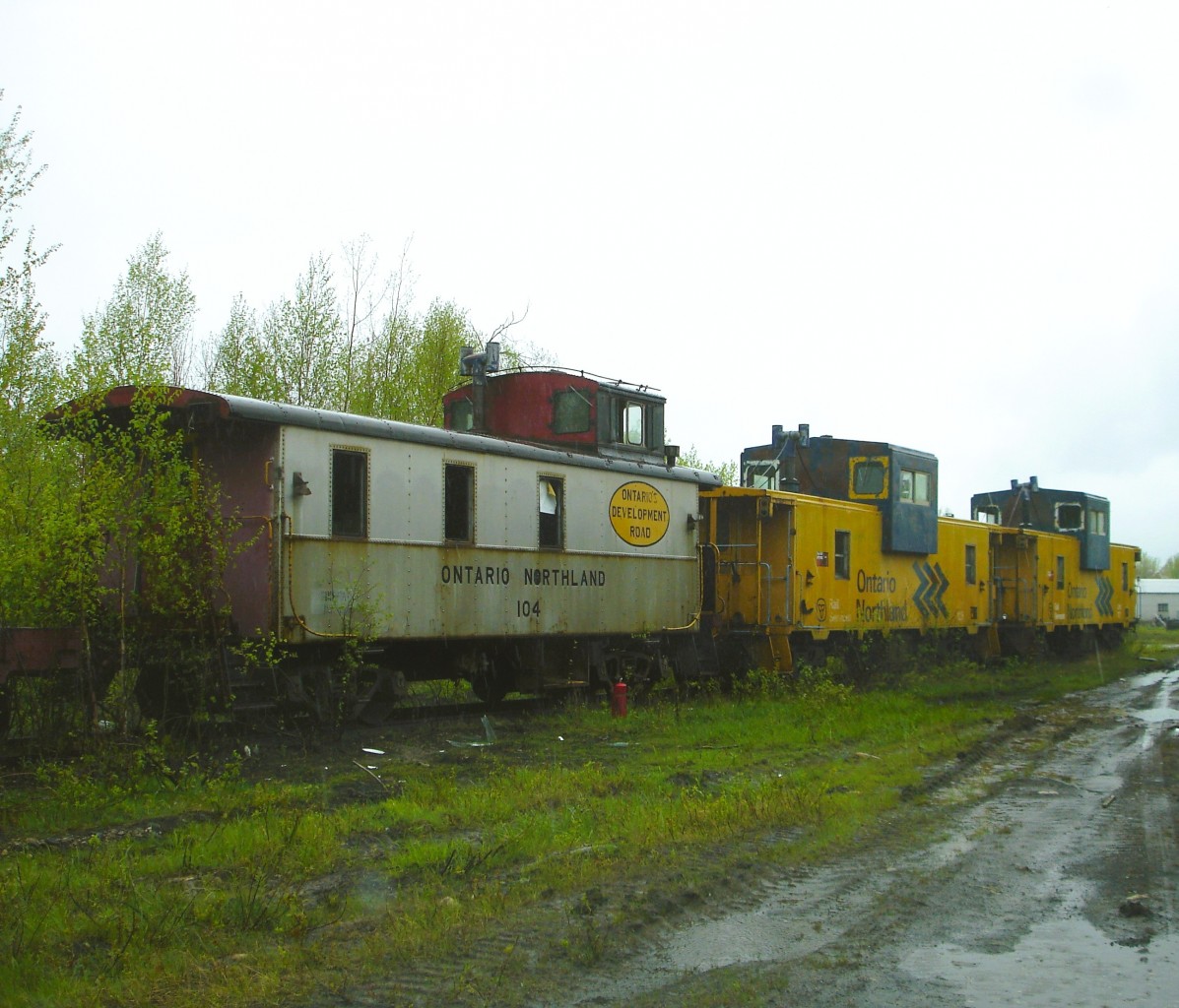 End of the train at the end of the line  
17 years ago today on May 19, 2009 ONT 104, ONT 125, and ONT 127 have reached the end of their days of bringing up the markers of ONR freights. 
It is an overcast and rainy day in ONR's North Bay yard which seems to magnify the sad end for this trio of cabooses. :-(