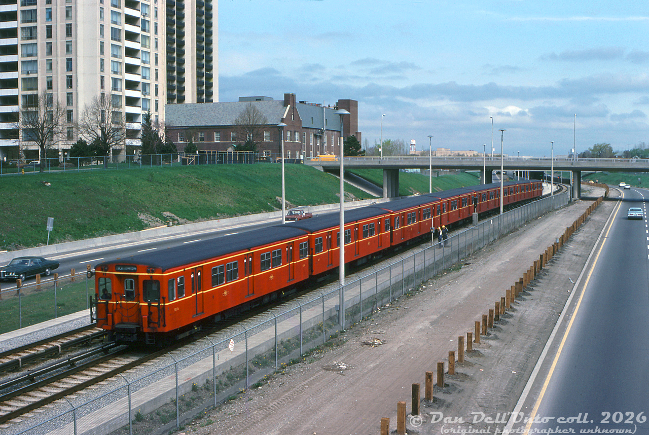 An 8-pack of the TTC's 1950's Gloucester G-series subway cars (the original Red Rocket subway cars built overseas in the UK for the Yonge line) head northbound past maintenance workers on the new Spadina subway line extension, ducking under Ridelle Avenue between Eglinton West and Glencairn subway stations. To achieve the full consist length, the shorter G-series cars were coupled up into trains of eight cars, versus trains of six of the regular 75' aluminum Hawker Subway cars.

While the new subway extension from St. George to Wilson opened in January 1978, work was still progressing on the nearby Allen Road (aka the failed Spadina Expressway). One idea that did survive all the grassroots and political fighting around the expressway construction was the idea of building a rapid transit line up the center of it, today reaching as far north as the City of Vaughan.

Original photographer unknown, Dan Dell'Unto collection slide.