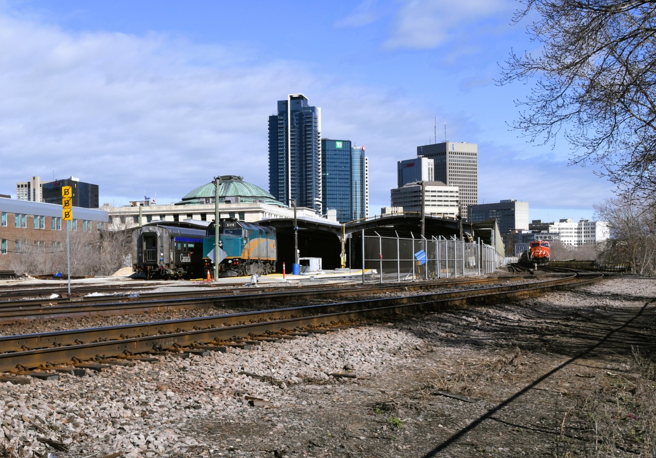The Shed  
At the left of the frame, VIA 6419 and unidentified VIA passenger car (VIA 8109 economy coach I think) sit partially under the canopy of the Winnipeg train shed, while at the right, stalled CN 3884 sits on one of the shed bypass tracks. 
The stalled freight caused an hour and a half delay in the departure of VIA 693 The Churchill train which gave me time for a few more photos and lunch at The Forks Market behind Union Station. :-)