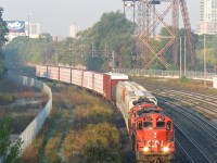 You can just taste the hazy, muggy, smoggy air some mornings in downtown Toronto, and this morning at Bathurst Street was no exception, with a thick haze visible in the air as CN local #543 puts in an appearance downtown, coming off the Oakville Sub and heading through the Union Station Rail Corridor to do some morning switching in the Toronto Portlands area to the east. Power today are GP9RM units 4107 and 7038, chugging slowly east on the "High Line" bypass amid all the morning <a href=https://www.railpictures.ca/?attachment_id=59168><b>GO Transit and VIA Rail action</b></a>. Don't forget to see the Toronto FC play some soccer at BMO Field this May 2007. The Inglis sign's wise words to the sleepy morning commuters on the Gardiner Expressway? "Your Dignity Can't Be Taken Away, Unless It's Surrendered"