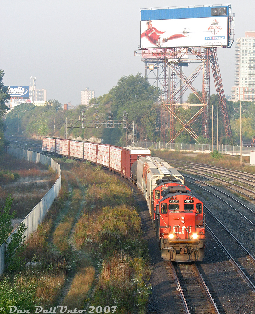 You can just taste the hazy, muggy, smoggy morning air some mornings in downtown Toronto, and this morning at Bathurst Street was no exception, with a thick haze visible in the air as CN local #543 puts in an appearance downtown, coming off the Oakville Sub and heading through the Union Station Rail Corridor to do some morning switching in the Toronto Portlands area to the east. Power today is GP9RM units 4107 and 7038, chugging slowly east amid all the morning GO Transit and VIA Rail action. Don't forget to see the Toronto FC play some soccer at BMO Field this May 2007. The Inglis sign's wise words to the sleepy morning commuters on the Gardiner Expressway this morning? "Your Dignity Can't Be Taken Away, Unless It's Surrendered"