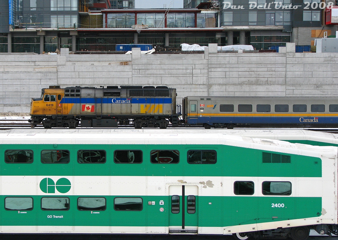 After finishing its morning run into downtown Toronto from Niagara Falls, VIA train #90 with F40PH-2D 6419 and 4 LRC cars backs its consist from Union Station to the Toronto Maintenance Centre in Mimico, passing GO bilevels laying over at Bathurst North Yard, and new Cityplace condos under construction on the former "railway lands" between Spadina and Bathurst Street (once home to the Spadina Coachyards, that the VIA TMC replaced in the mid-80's).