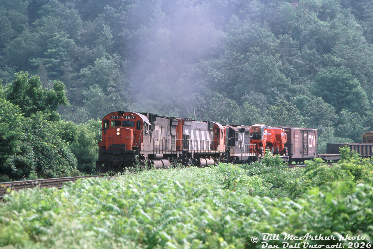 CN C630M 2017, M636 2339 and GP9 4509 grind upgrade with train #401, about to roll though Dundas on the Dundas Sub. A pair of farm combine loads ride the first flatcar behind the Geep.

Bill McArthur photo, Dan Dell'Unto collection slide.