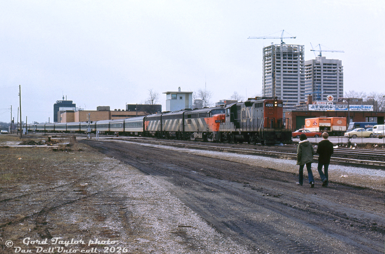 Back in the era of long passenger trains with the power to match, CN GP9 4103 leads an A-B-A set of FPA4 6770, a 6600-series F9B and 6500-series FP9 on an eastbound passenger train, at least 12 cars long, leaving London Station (the black office tower of which is visible in the distance). The units have just crossing Colbourne Street, with two pedestrians leasurely strolling into view alongside the track.

Gord Taylor photo, Dan Dell'Unto collection slide.