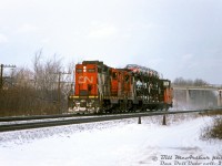 CN GP9's 4590 and 4573 hustle westbound through Aldershot by Lemonville Road, with what must have been a single "hot rack" load in tow full of brand new Ford Tempos and Mercury Topazes from the Ford plant in Oakville. At the time CN's GP9RM rebuilt program was underway, and trailing unit 4563 would soon be rebuilt into GP9RM 7227 later that year. 4590 would become 7065 in 1992.
<br><br>
<i>Bill McArthur photo, Dan Dell'Unto collection slide.</i>