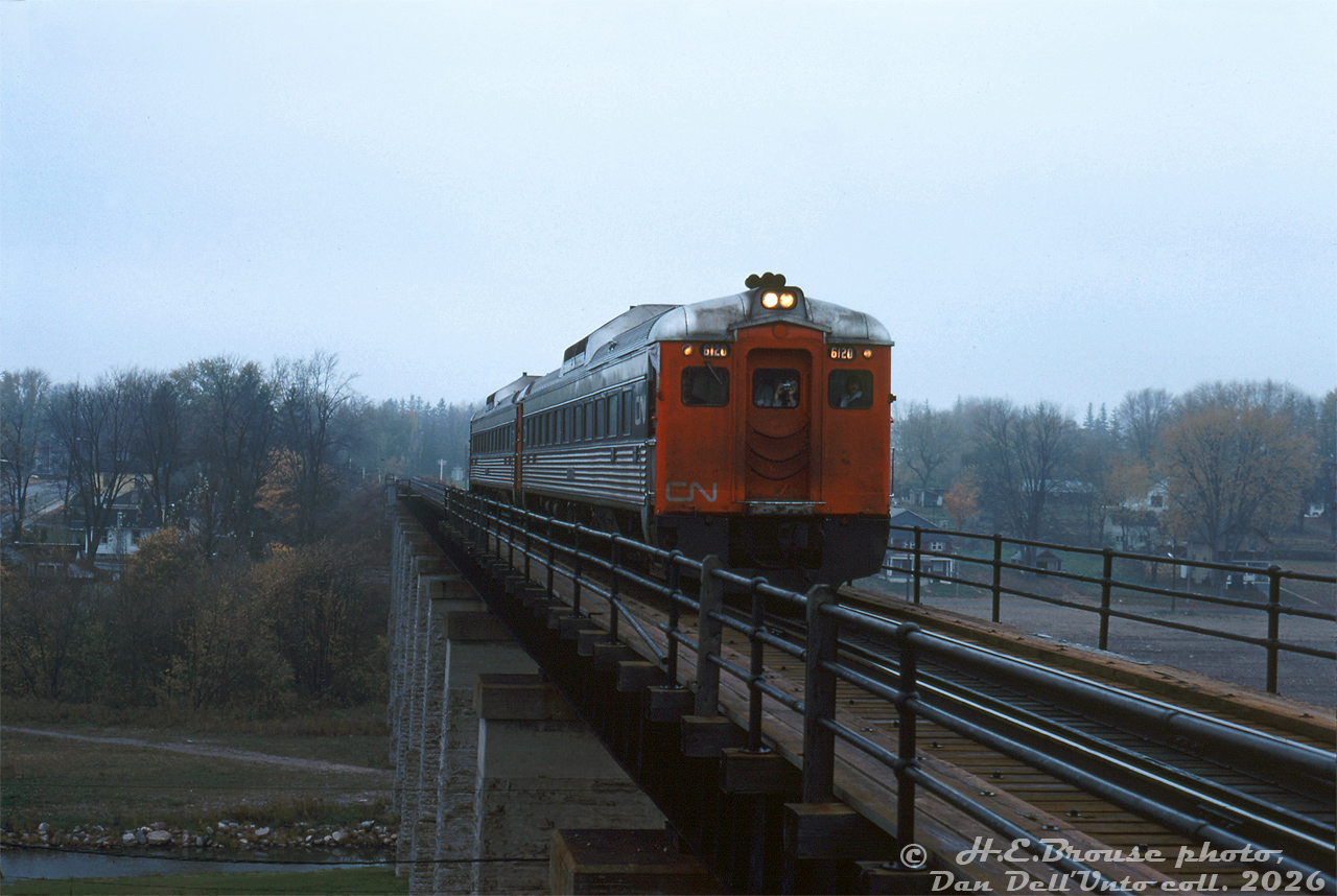 CN RDC-1's 6120 and 6119 cross the bridge over Trout Creek in St. Mary's on a gloomy rainy day, operating on a fantrip around Southern Ontario. Some attendees are visible aboard during this photo stop/run-by, including one bearing a camera. Photo stops included Lucan Crossing, Forest, St. Mary's Junction, St. Thomas, and a visit to Port Stanley.

Harold E. Brouse photo, Dan Dell'Unto collection slide.