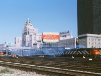 Pulling out of Union Station in downtown Toronto, CN's eastbound "Lake Shore Limited" departs from Track 2 with an A-B-A set of cowl units providing the power today. CN FPA4 6774, F9B 6620, and FPA4 678? start off the journey with some white smoke, after idling awaiting their departure time. CP Rail's (CP Hotels) Royal York Hotel can be seen prominently in the background across from the main Union Station building, with the Dominion Public Building on the right, almost all matching in colour. Behind the train are the old CP Express sheds (eventually demolished for the <a href=https://www.railpictures.ca/?attachment_id=58241><b>2000's GO Transit bus terminal</b></a>). One of the striking new black TD towers can be seen, the Toronto skyline not yet populated with a wall of office towers and high rises. That "Spans the World" Bank of Montreal billboard on top of the CP Express building is reminiscent of a similar old CP slogan from the 1940's-50's.
<br><br>
<i>Original photographer unknown, Dan Dell'Unto collection slide.</i>