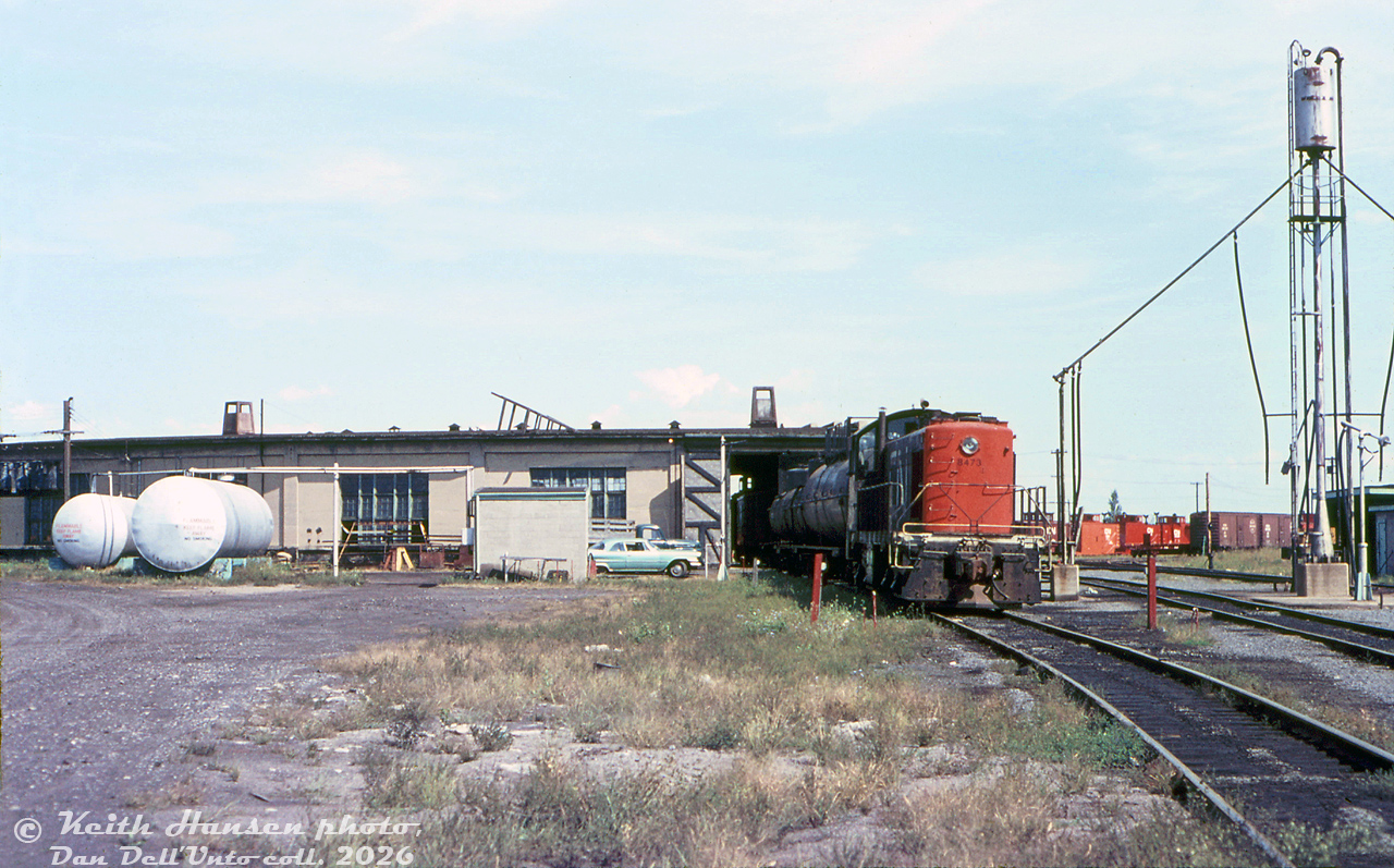 CN S3 8473 spots some cars behind CN's Belleville Roundhouse. Since they're both tank cars and the engine servicing facilities are alongside on the right, they might be spotted here for unloading diesel fuel into those large white tanks marked "FLAMMABLE, KEEP FLAMES AWAY, NO SMOKING" in big lettering (just a guess...). Some snowplows and boxcars can be seen near the turntable area in the distance. There looks to be a flanger or caboose visible inside the roundhouse (perhaps this was an indoor car repair track?).

Keith Hansen photo, Dan Dell'Unto collection slide.