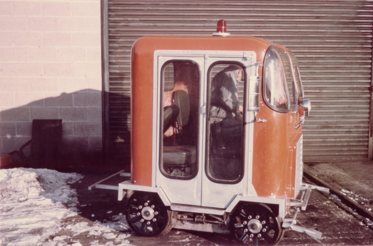 Futuristic look, high-tech track motor car, 1970 style  
CN 999-82 is a 2-man inspection track motor car with experimental welded aluminum chassis and fiberglass cab with bi-fold aluminum doors. 
An attempt to make the conventional track motor car a little more 'user friendly' with lightweight aluminum frame, fully enclosed operator compartment, front windshield wipers, headlight, red flashing roof beacon, and west coast mirrors. 
The car as shown did not get purchased in any quantity by CN at the time, but it helped lead the way to continued improvements in future track motor car construction, safety, and crew comfort. 
Photo taken at the Danforth Work Equipment shop located at the rear of 2314 Gerrard St. East Toronto, ON which is now a cluster of town homes. 
 http://www.railpictures.ca/?attachment_id=42224