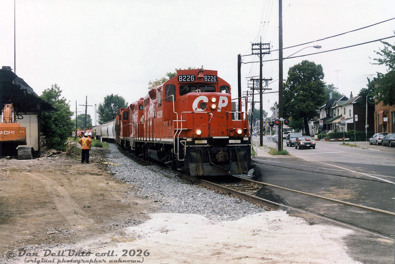 CP GP9u 8226, probably on one of the Emery Turns, heads south on the MacTier Sub connection track enroute the West Toronto/Lambton Yards, crossing Old Weston Road and passing railway employees and demolition crews with their Hitachi excavator in the process of tearing down the old CN West Toronto Station.

The demolition of CP's West Toronto station has been well-covered in the past, but demolition of CN's West Toronto Station to the north has received little attention. It continued to see passenger use into the 1980's under VIA Rail, but by 1990 any passenger stops were gone (possibly a victim of the 1990 VIA cuts). Its importance also likely diminished when GO Transit started Georgetown line operations in 1974 and opted for their own new GO station at Bloor Street, closer to the TTC's Bloor-Danforth subway, rather than using CN's existing station here. According to notes by the late Toronto railway historian Derek Boles, both the CN station and express shed were severely damaged by a three-alarm fire on October 21st 1993, after being vacant/out of use for a number of years prior. Photos after show it boarded up in a state of decay (the roof on the north end was much more damaged, and falling in). A bit more digging shows the station was eventually demolished years later around August 1999, after suffering from the aforementioned fire and years of vandalism. The vacant CN property in the middle of both CN and CP rail lines then became a compound yard for storing City of Toronto contractor snow removal equipment (with parts of the old station platform still visible), but was eventually all obliterated for the Metrolinx/GO West Toronto grade separation trench.

Original photographer unknown, Dan Dell'Unto collection print.
Note: this photo was a scan of an old print purchased from a train show back in the early 2000's, probably at one of the large annual CARM ones held at the Toronto Congress Centre every year. Unfortunately, no photographer or description was noted on the print, but from research I was able to narrow the demolition down to 1999.