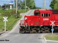 An extra CPKC Wolverton Job with GP38-2 3040 and GP20C-ECO's 2307 and 2259 is viewed about to cross Greenfield Road in Ayr, Ontario on the Ayr Pit Spur. The crew was returning to Wolverton after setting-off auto racks on the Waterloo Subdivision for the Toyota Plant in Cambridge. However, they had a lengthy stop at Ayr to switch the busy FS Partners facility on the spur. 