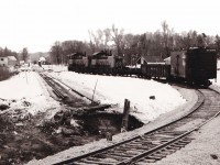With a brakeman riding the rear, a pair of SW1200RS units take a few cars around the newly completed diversion track between the CNR Coldwater spur and the remnant of the CPR Port McNicoll subdivision.

This connecting track permitted CP to reach the CNR Midland sub at Coldwater when the large Hoggs Bay trestle was abandoned in 1971. A similar connecting track was built between McMillan on the Midland sub and the yard at Port. Prior to this CP had an interlocked  diamond crossing of the CN spur. CP used trackage rights on CN to reach McMillan until 1991 when the Port McNicol sub was abandoned. The diamond remained in place for several years until the unused rails were lifted between this point and the trestle.

The connecting track originally dipped south of the existing track before connecting to the existing track near the bridge over the Coldwater river. The connecting track was later reconfigured to a more conventional turn in the 1980's due to difficulties with long trains. Six axle units were prohibited on this later track arrangement. Our family rode a UCRS excursion to Midland that went through this trackage in 1975. It was an interesting sight watching the 80 foot long coaches negotiate the shoofly.

Visible in the background is the CPR Coldwater station with some work service cars in the siding. Between the bridge and flanger sign is visible one of the ancient crossing signs with a danger light on top of the post. This signal is now displayed at the Coldwater Museum.

The County of Simcoe mapping website (https://opengis.simcoe.ca/public/) has aerial views of this area. The 1978 and 1983 views show the two different layouts.

Unknown photographer from my collection.