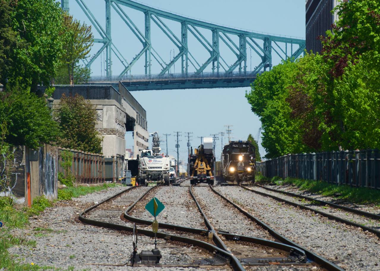 IC 9628 leads CN 500 as it passes MOW vehicles at the western end of Port of Montreal trackage.