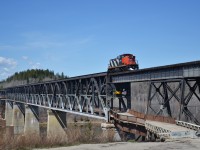 Due to increased road traffic, a newer bridge was was constructed in 1973, further to the north when compared to the original double deck bridge. The lower deck was finally closed to cars in 2021 due to the rapidly deteriorating conditions of the roads surface below, with small holes in the roads surface appearing, you’re able to see the Saskatchewan River below.

The crew told me a story that for one rather impatient individual, the drive to the north was too much of an inconvenience for them.

Someone had driven up the eastern side of the bridge along the service road, aligned their car with the tracks direction and proceeded to let the air out of the tires, allowing the rims to straddle the rails, with the rim acting as the flange on both sides. The individual crossed the upper deck of the bridge, minus guard rails, to the other side and eventually disembarked at the next crossing. 

I couldn’t imagine staring down at the river with no barriers on either side in a car, but the crew graciously allowed me to stand on the walkway as we crossed over into Nipawin from the West. The view was downright spectacular, in May in that part of the province, winter seems to hold on just a little longer some years. The May thaw and melt provided a swollen Saskatchewan River, adding to the ambiance of the crossing. 
