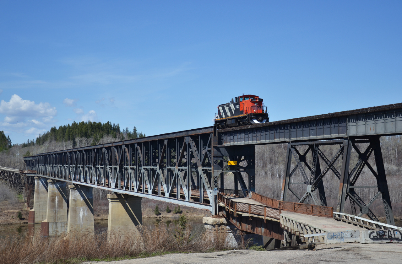 Due to increased road traffic, a newer bridge was was constructed in 1973, further to the north when compared to the original double deck bridge. The lower deck was finally closed to cars in 2021 due to the rapidly deteriorating conditions of the roads surface below, with small holes in the roads surface appearing, you’re able to see the Saskatchewan River below.

The crew told me a story that for one rather impatient individual, the drive to the north was too much of an inconvenience for them.

Someone had driven up the eastern side of the bridge along the service road, aligned their car with the tracks direction and proceeded to let the air out of the tires, allowing the rims to straddle the rails, with the rim acting as the flange on both sides. The individual crossed the upper deck of the bridge, minus guard rails, to the other side and eventually disembarked at the next crossing. 

I couldn’t imagine staring down at the river with no barriers on either side in a car, but the crew graciously allowed me to stand on the walkway as we crossed over into Nipawin from the West. The view was downright spectacular, in May in that part of the province, winter seems to hold on just a little longer some years. The May thaw and melt provided a swollen Saskatchewan River, adding to the ambiance of the crossing.