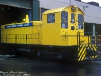 General Motors of Canada Ltd SW900 47074 sits inside the grounds of GM's former McKinnon Industries <a href=http://www.railpictures.ca/?attachment_id=38658><b>St. Catharines plant</b></a> (foundry/casting work), looking clean and near spotless on this wet day. This yellow switcher was originally built by GMD London in 1966 for McKinnon Industries, later acquired by GM of Canada. It was eventually sold to Dofasco in Hamilton and became their <a href=http://www.railpictures.ca/?attachment_id=47792><b>416</b></a>.<br><br>The 900hp single stack SW900 model, powered by an 8-cylinder 567C, was part of EMD/GMD's common switcher platform line at the time and was in the middle range of their product offering: less powerful than the 12 cylinder 1200hp SW9/SW1200 model, but more powerful than the 6-cylinder 600hp SW1/SW600. It (and its 800hp predecessor SW8) were popular for light switching and industrial use.<br><br><i>Roger Heed photo, Dan Dell'Unto collection slide.</i>