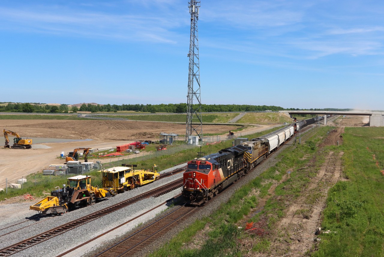 Eastbound (M392) operating DP 2-1-0 makes it way through Ash passing on going construction works for the future Milton Logistics Hub. The recently completed overpass supports the access road off Britannia Road. In the distance grading continues for the yard tracks. A ballast regulator and production/switch tamper are at the ready to lift and surface the freshly ballasted future north and south tracks toward Derry.