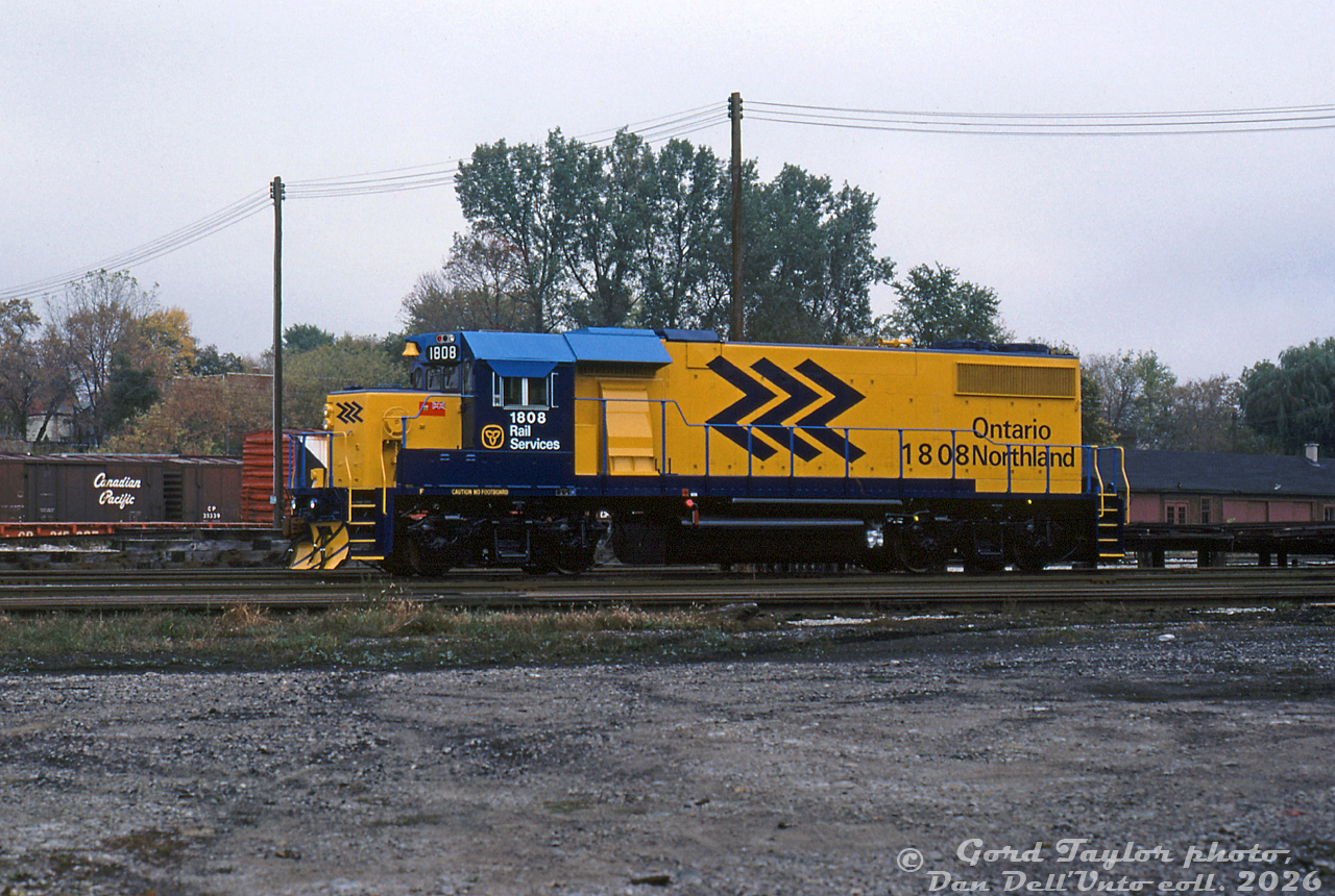 A brand new GMD GP38-2 brightens up a gloomy day down at CP's Quebec Street yard in London: Ontario Northland 1808, freshly outshopped from the nearby GMD London plant, sits awaiting forwarding to its owner in northern Ontario. It was part of a two unit order built in 1984 (units 1808-1809), numbered above ONR's existing eight units 1800-1807. These were later production units featuring Q-fans, corrugated radiator grills, and angled "laundry chute" blower housings, on top of most of the usual "Canadian" spotting features such as nose headlight, tri-colour class lights, numberboard-mounted bell, vertical Canadian steps/handrails, and showshields behind the cab.

Gord Taylor photo, Dan Dell'Unto collection slide.