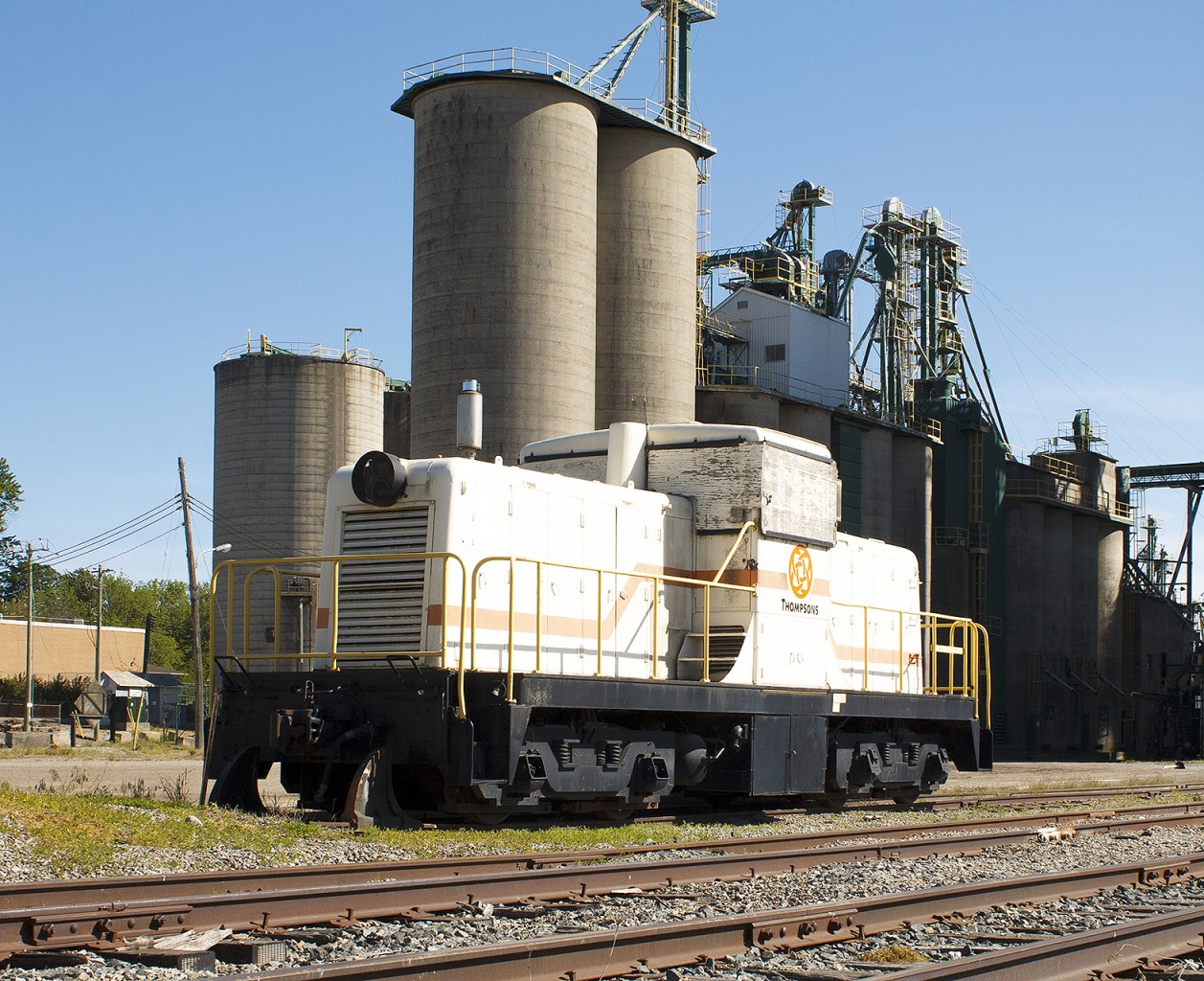 This old engine sat on the siding for months prior. Each time I passed it going to the local indoor pool with the kids, I wished I had my camera. This time, due to the chase of local freight CN 514, i had it! And boy am I glad i did. 

From fellow contributor Luke Bellefleur, using information posted on the site "Old Time Trains":  Thompsons # nil in new paint scheme and window protectors. Acq. 2/2013 ex Bucyrus-Erie 8302 South Milwaukee, WI nee Normetal Mining # nil. 80-ton GE 28481 10/1946.


With it boarded up, I knew time wasn't on my side. Next day after this photo, the engine was loaded onto a flatbed truck and hauled away. To where? Not exactly sure, but the next morning my boss came into work quite excited. Tells me his story:"You'll never guess what I did, I followed an engine all the way home!" Last known sighting was just inside the sleepy city limits of Kent Bridge, Ontario. Destination still unknown to this contributor.