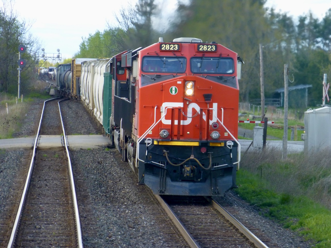 On 5/15/2016 westbound ES44AC 2823 moves through the turnouts on the very short piece of single track at Stewarttown Mile 26.6 on CN's Halton Sub just west of of Georgetown. 
I know that you foam..er i mean fans out there will know the answers to these questions.
Why is there a broom on the front of the locomotive?

What is the reason for the red light above one of the ditch lights? 

What are the white objects on the roof of the locomotive for?